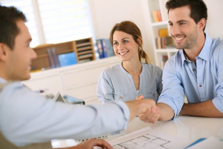 Young couple shaking hands with dapper immigration consultant in Toronto living room