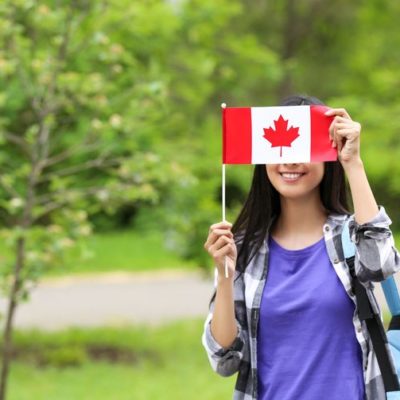 Young Canadian immigrant holding Canada flag in front of face