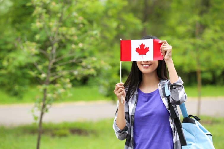 Young Canadian immigrant holding Canada flag in front of face