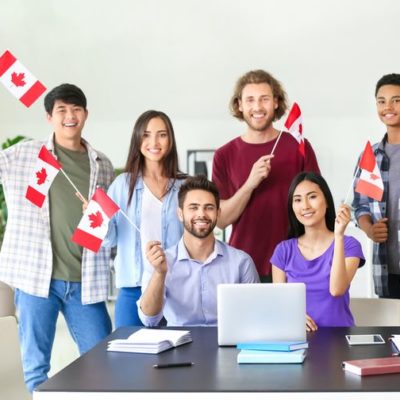 Diverse group of young Canadian immigrants waving Canadian flags