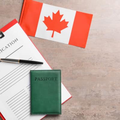 Visa application form, passport and Canadian flag on table. Concept of immigration