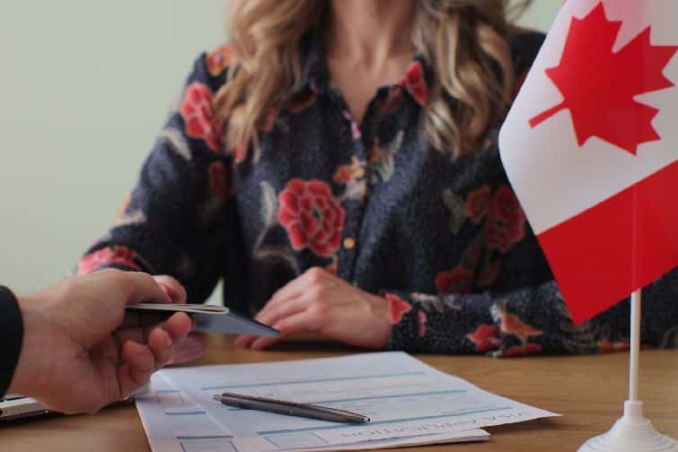 Canadian woman consular officer giving passport to male immigrant, work visa, citizenship. Visa Application online form immigration concept. Visa approval.