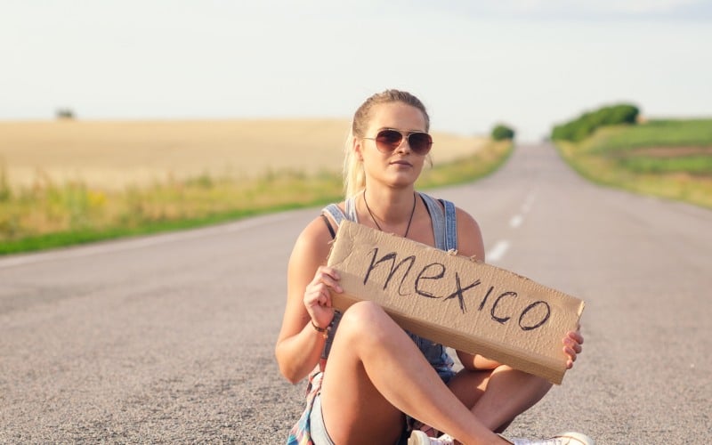beautiful girl hitchhiking on the road traveling