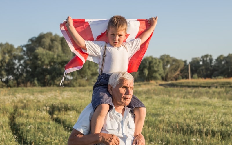 attractive old senior man grahdson-holding-canadian flag national holiday