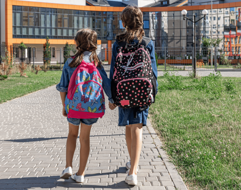 Girls with backpacks near school outdoors